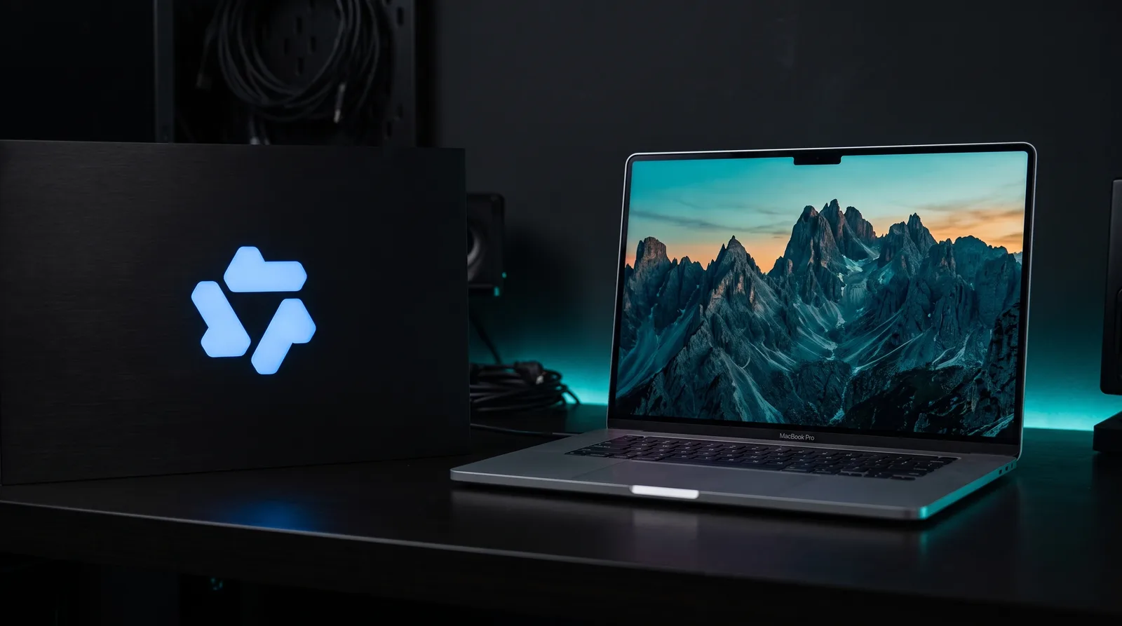 Illuminated Qwen logo on a black panel next to a MacBook Pro showing a generated mountain landscape